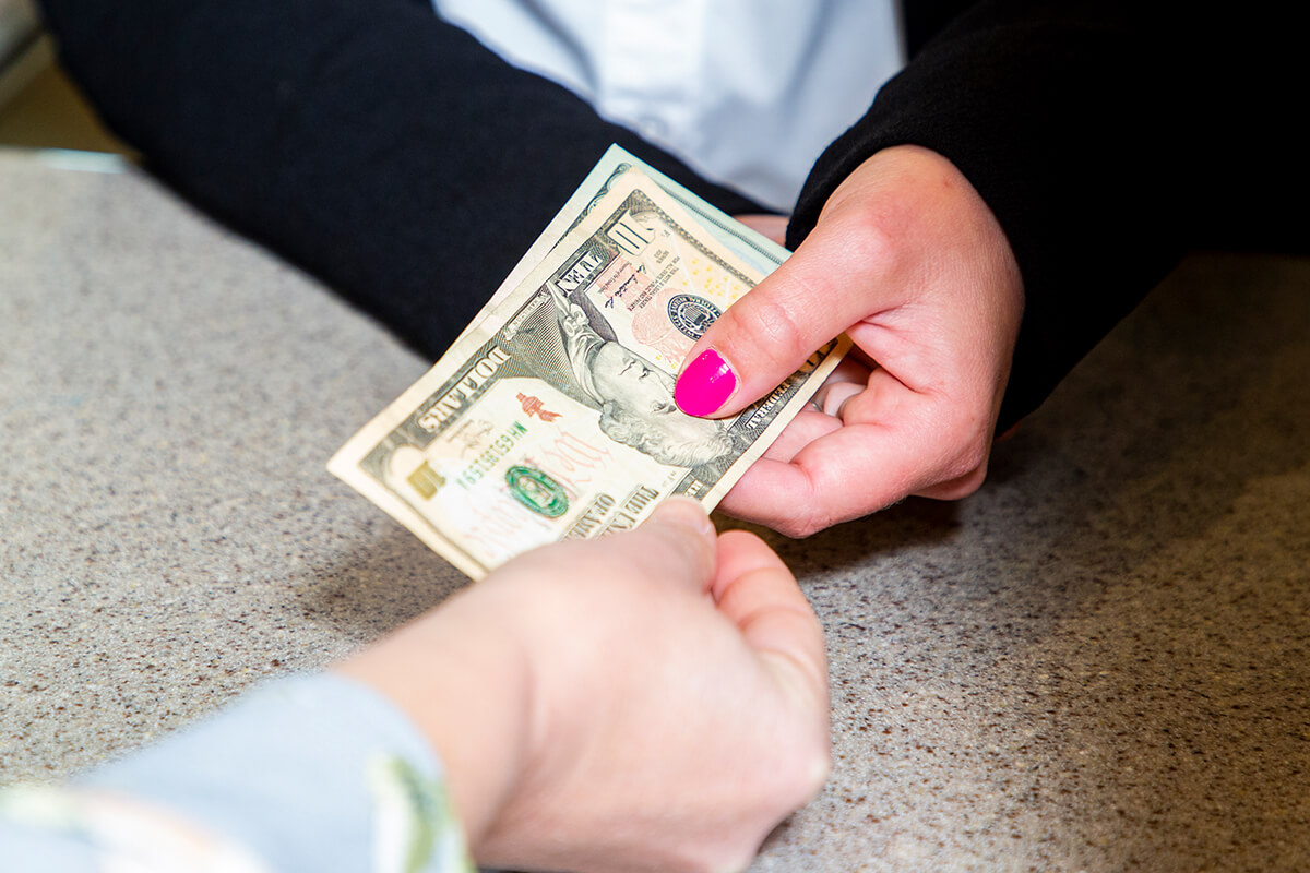 Photo of teller handing customer cash.