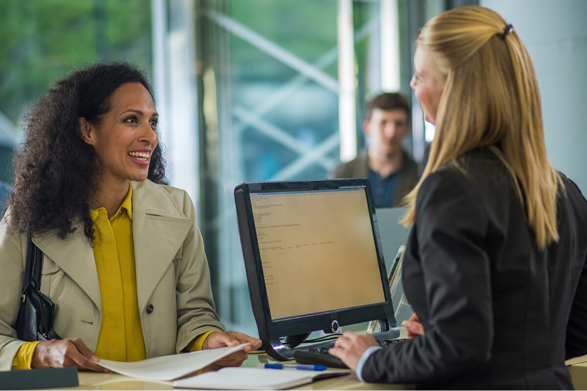 A customer standing at a tellers desk receiving help